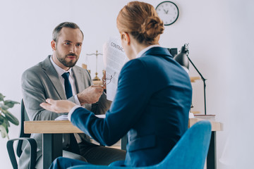 partial view of lawyers discussing contract during meeting in office