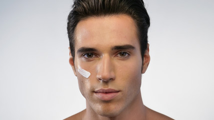 Fototapeta premium Close up of a man with moisturizer for his face smiling because he hydrates his skin and protects against impurities with anti-aging effects. Concept of: beauty and body care, creams, skincare