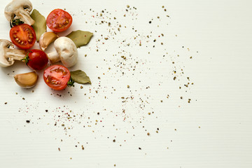 cherry tomatoes, champignons, bay leaves and garlic on a white background
