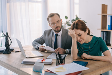 lawyer and client discussing contract at workplace with laptop in office
