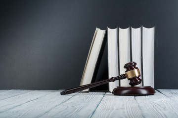Law concept - Open law book with a wooden judges gavel on table in a courtroom or law enforcement...