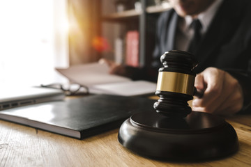 Justice and law concept.Male judge in a courtroom with the gavel,working with,digital tablet computer docking keyboard,eyeglasses,on wood table 
