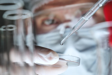 In a futuristic laboratory, a scientist with a pipette analyzes a colored liquid to extract the DNA...