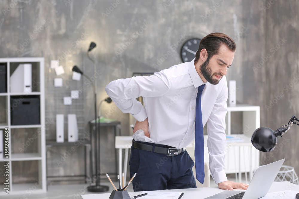 Canvas Prints Young man suffering from back pain in office