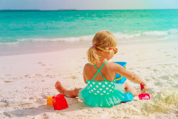 cute little girl play with sand on beach