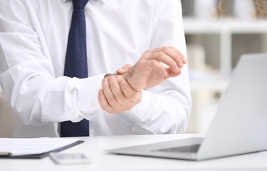 Young man suffering from wrist pain in office