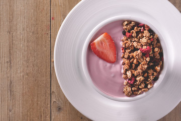 Composition of a typical genuine breakfast made with strawberry yogurt and granola. Concept of: fitness, diet, wellness and strawberries.