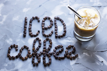 A glass of iced coffee with milk next to the inscription 