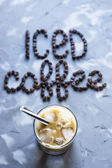 A glass of iced coffee with milk next to the inscription 