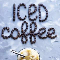 A glass of iced coffee with milk next to the inscription 