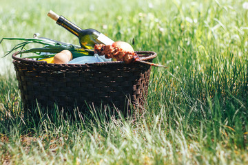 Picnic basket with food on green sunny lawn.