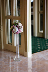 Flowers bouquet in a glass vase at wedding reception entrance.