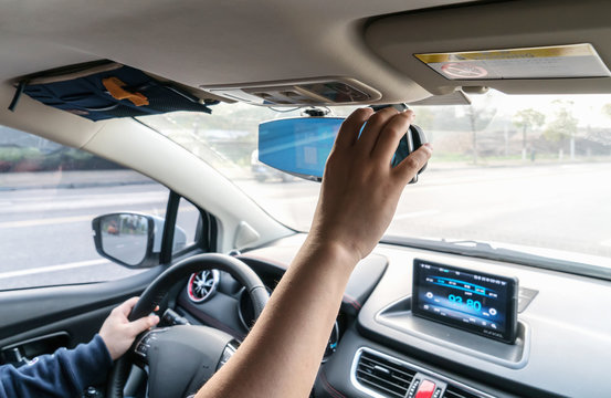The man adjusted the rearview mirror in the car