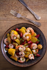 Shrimp boil. Shrimps, smoked sausages, potatoes and corn in bowl on wooden table. overhead, vertical
