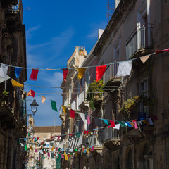 Street in Ortygia, Syracuse decorated with multi-colored festive buntings.