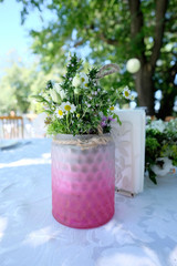 Setting a wedding table. Flowers in a glass cup ornament on a wedding table reception event.