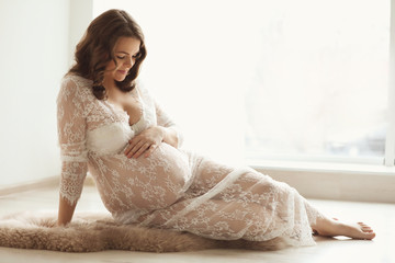 Naklejka premium Young pregnant woman in elegant dress at home