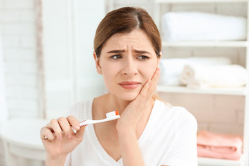 Young woman suffering from toothache indoors