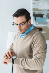 Handsome man in glasses looking at his watch
