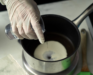 Step-by-step preparation of black designer cake. The confectioner prepares cream with cheese brie for cake.