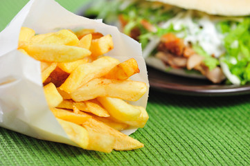 Fast food. Fries in paper bag isolated against blurred background.