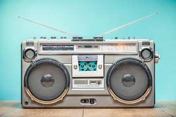 Fototapeta premium Retro przestarzały przenośny radioodbiornik stereo boombox z magnetofonem kasetowym z około późnych lat 70. na tle ściany w kolorze akwamarynu. Koncepcja muzyki słuchania. Zdjęcie filtrowane w starym stylu vintage