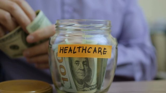 Caucasian man putting a glass jar put in a drawer table with his savings for future healthcare