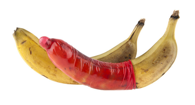 red condom and old, ripe banana isolated on white background