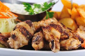 Grilled chicken leg with garnish. Grilled chicken leg with with garlic sauce, baked potatoes, cabbage salad and parsley.