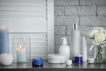 Body care cosmetics and burning candles on table