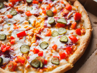 Cheeseburger pizza in delivery cardboard box on white table