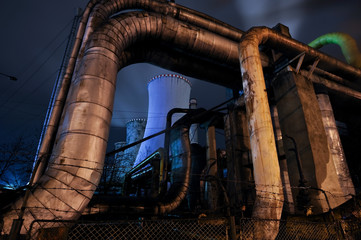 Thermal power plant by night. Pipes for transporting water from power plant with big furnace in the background.