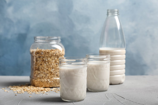 Jars with oat milk and flakes on table