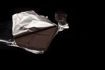 Chocolate bar wrapped in aluminum foil in the dark ..