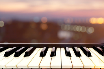 Closeup on perspective of Piano keyboard musical instrument with twilight bokeh background.