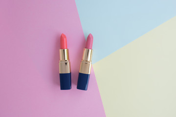 Flat lay of creative female cosmetic for pink and orange lipstick on the colorful background with copy space