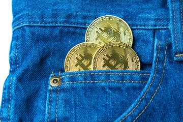 Golden bitcoins in the pocket of old vintage indigo stonewashed jeans. Concept of virtual currency in real life. New currency of the future. Modern trendy color