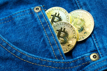 Golden bitcoins in the pocket of old vintage indigo stonewashed jeans. Concept of virtual currency...