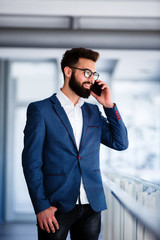 Busy Young Businessman Talking On Cellphone At Workplace