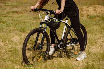 Bicyclist at the summer sunset on the desert road in the reserve territory. Full length image of female bicycle. Extreme mountain bike sport athlete woman riding outdoors lifestyle trail