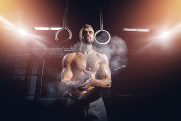 Strong man with muscles prepares before training using dust of magnesium workout. Concept cross fit, gymnast training - obrazy, fototapety, plakaty