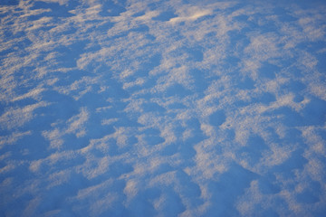 Snow field on sunset with blue shadows. Background texture. High angle view. Copy space.