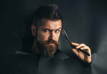 Barber shop equipment. Barbershop concept. Serious bearded man holds razor, looking through paper....