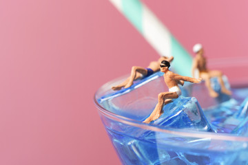 miniature men in swimsuit on a cocktail.