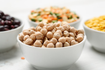 Chickpea and other beans in white bowls on a wooden table