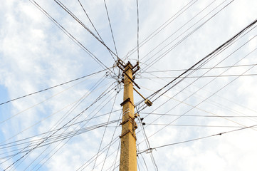 Many wires strained on one power line pole on the background of the sky