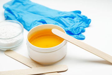 Wax for depilation with blue gloves and other tools on a white background