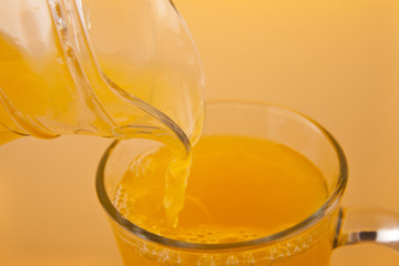 orange juice pouring into a glass on an orange background
