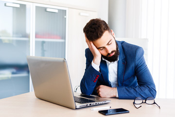 Young Sleepy Businessman Sitting At Workplace