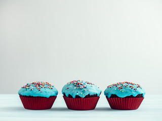 Festive, fragrant cupcakes, covered with turquoise glaze and bright decoration for baking on a white background
